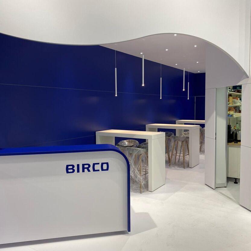 Eleganter Empfangsbereich mit dynamischen blauen Wänden, weißem Tresen und minimalistischen Hängeleuchten