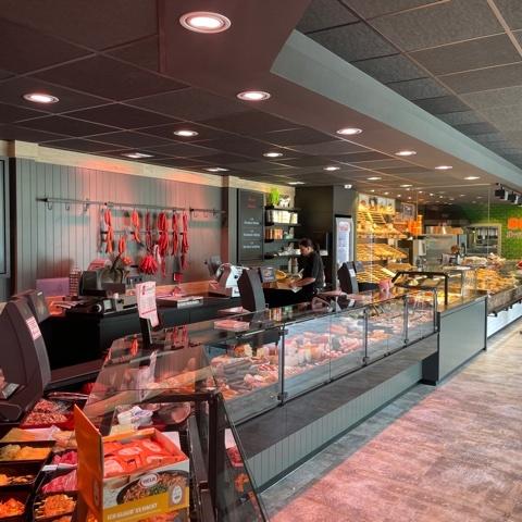 Moderne Fleisch- und Backwarentheke mit dunkler Decke, Glasfronten und durchgängigem Ladenbaukonzept