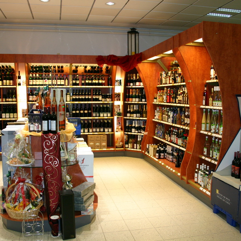 Weinregale mit gebogener Holzstruktur und zentraler Präsentation im umfassenden Ladenbaukonzept