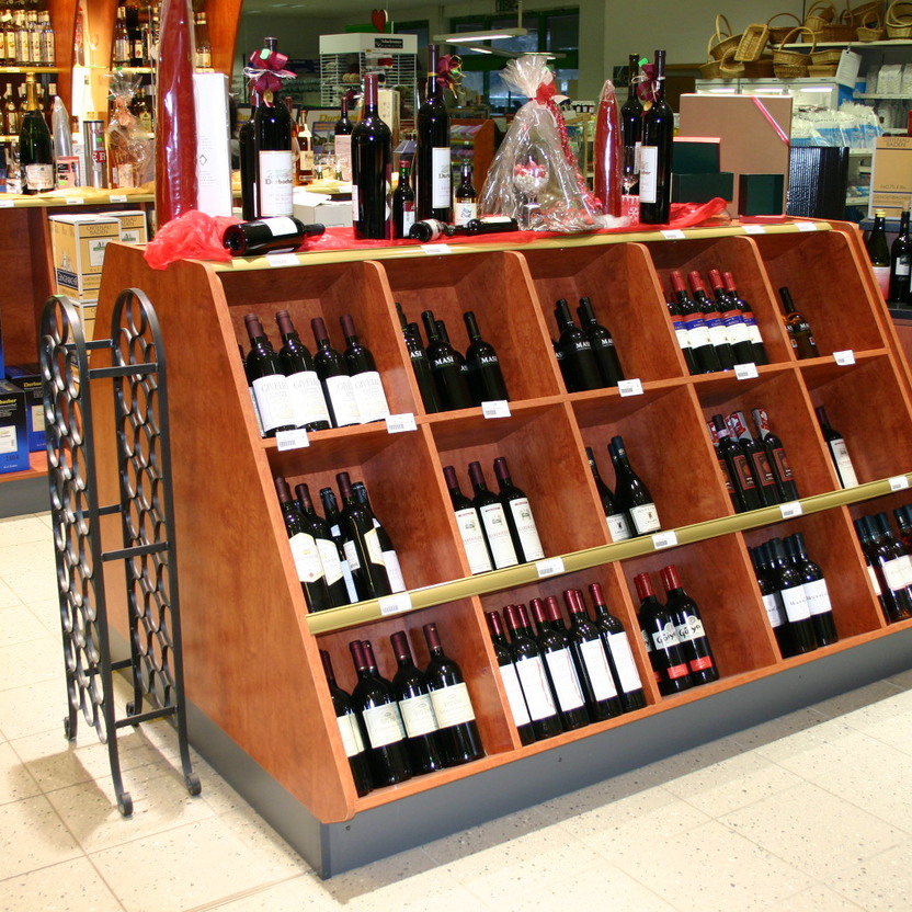 Schräg gestellte Holzfächer mit Weinflaschen auf freistehendem Ladenbaumodul im Verkaufsbereich