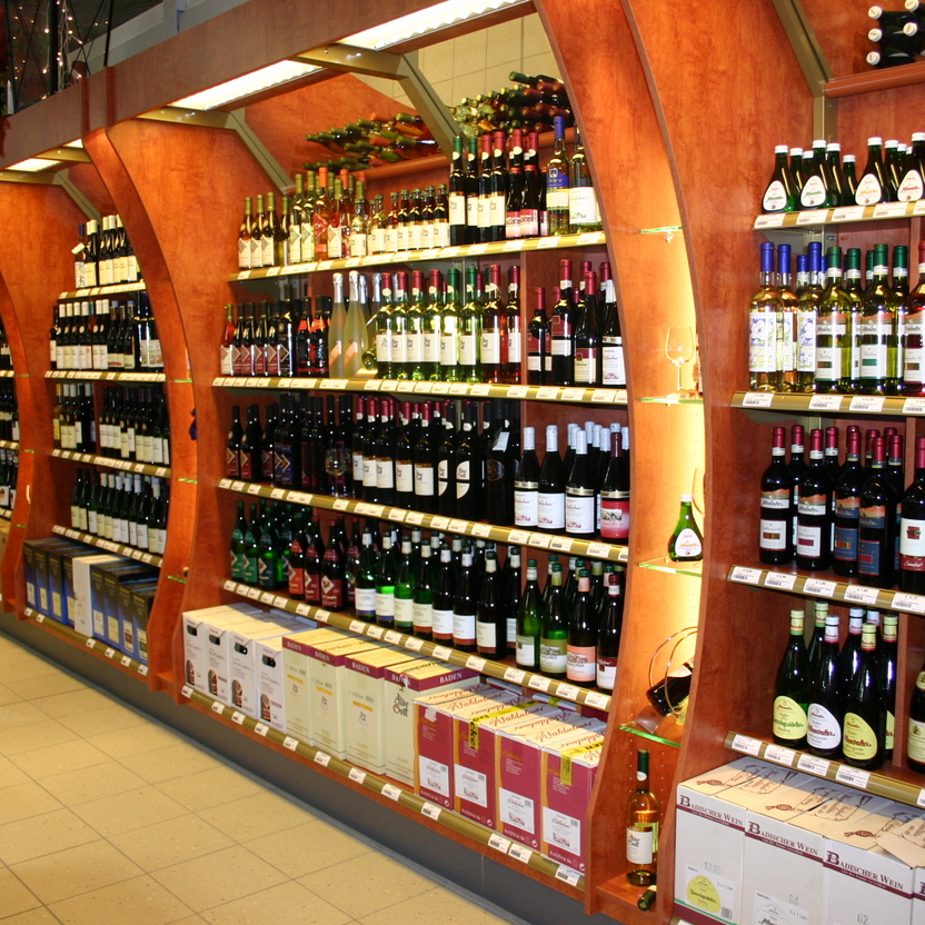Warme Holzregale mit Weinflaschen, Segmentbögen und durchdachtem Ladenbau für Getränkeabteilung