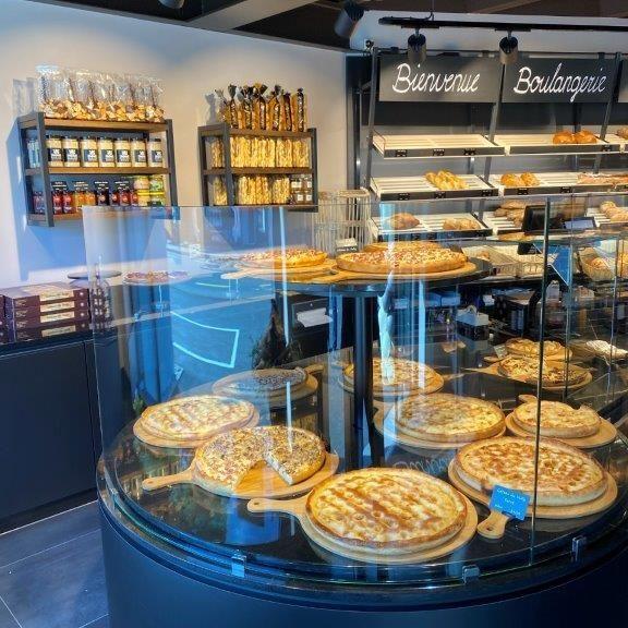 Runde Theke mit herzhaften Tartes, modernen Regalen und elegantem Ladenbau im Bäckereistil