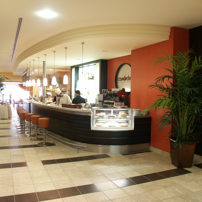 Großzügiger Barbereich mit Sitzplätzen, Deckenleuchten und gebogener Theke im modernen Ladenbau