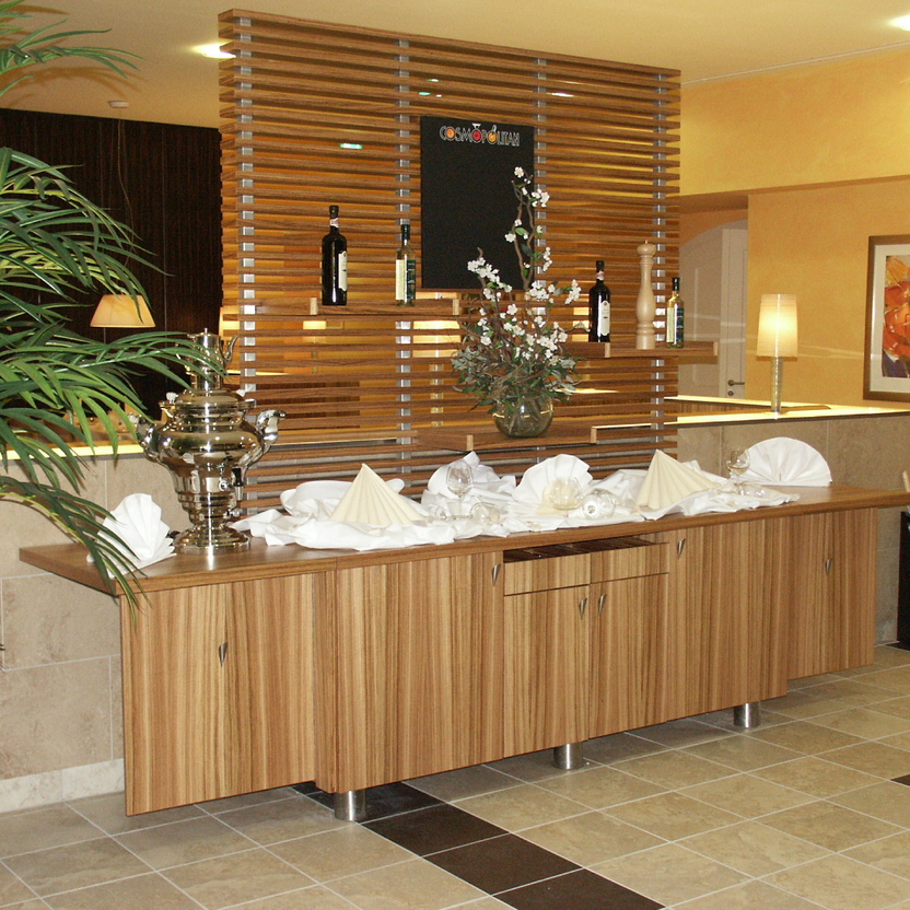 Holzfront mit dekorierter Anrichte, Raumteiler mit Flaschen und floralen Elementen im Ladenbau