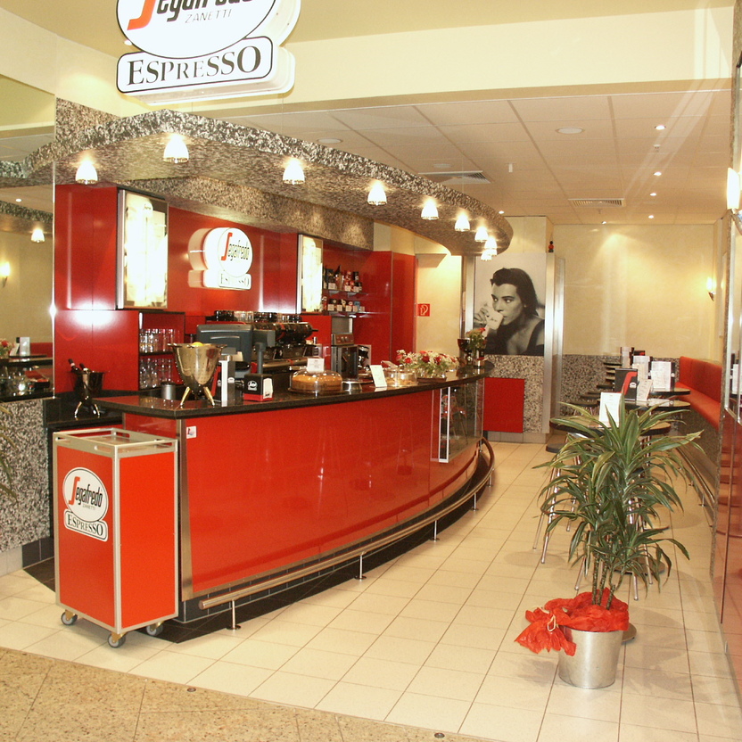 Kompakte Espresso-Bar mit Theke, Sitzbereich und stilvollem Ladenbau in Rot und Steinoptik